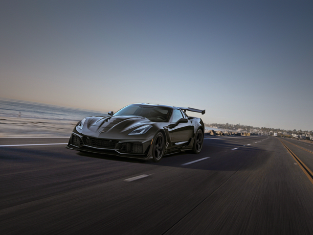 Dark grey Corvette car driving down a road
